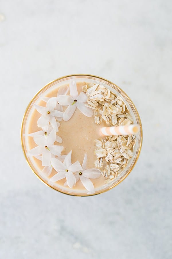 Peach smoothie with jasmine flowers, rolled oats and a paper straw