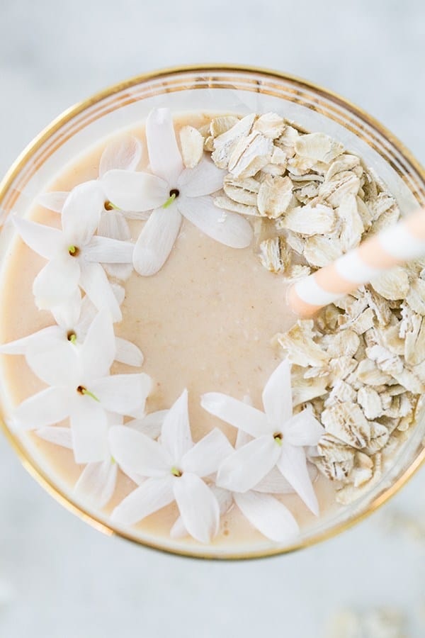 Close up picture of a smoothie with flowers and oats.