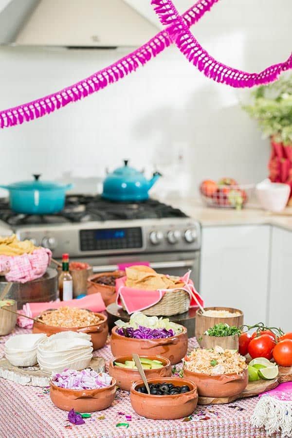 Colorful taco party with toppings in bowls.