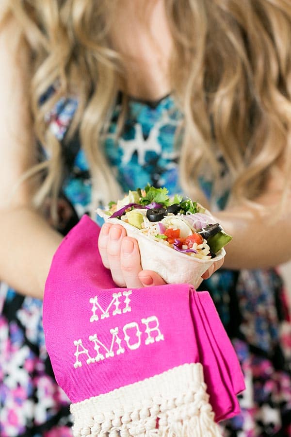 Girl holding a taco bowl filled with toppings. 