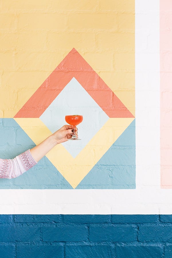 Holding a cocktail in front of a pretty wall.