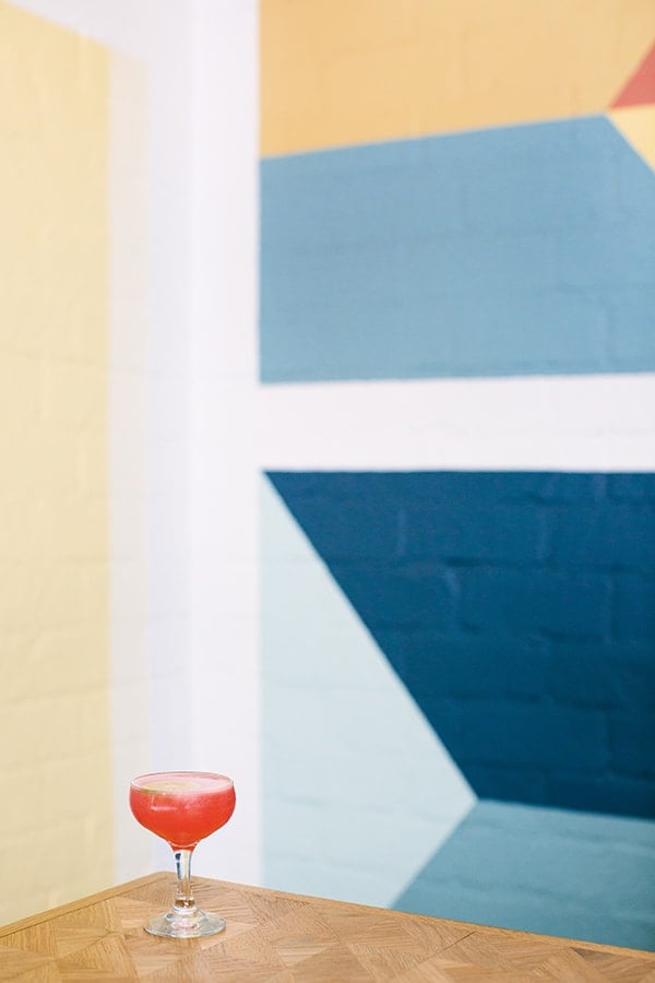 Cocktail in front of colorful block wall.