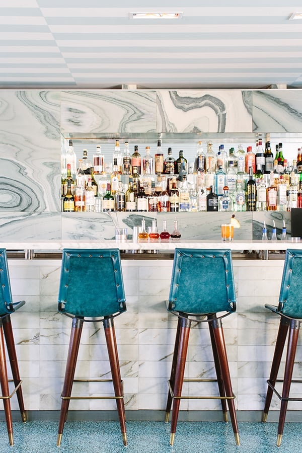 Beautiful marble and bar with green chairs.