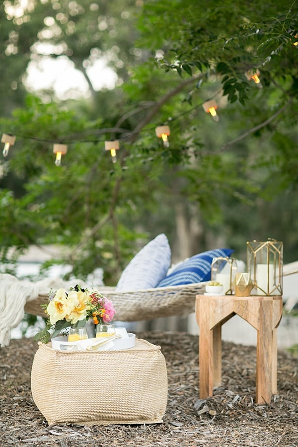 Outdoor hammock oasis with a pouf and a side table and outdoor lanterns