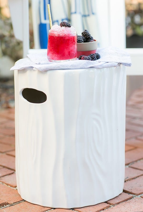 A white ceramic stool with a boozy snow cone and blackberries.