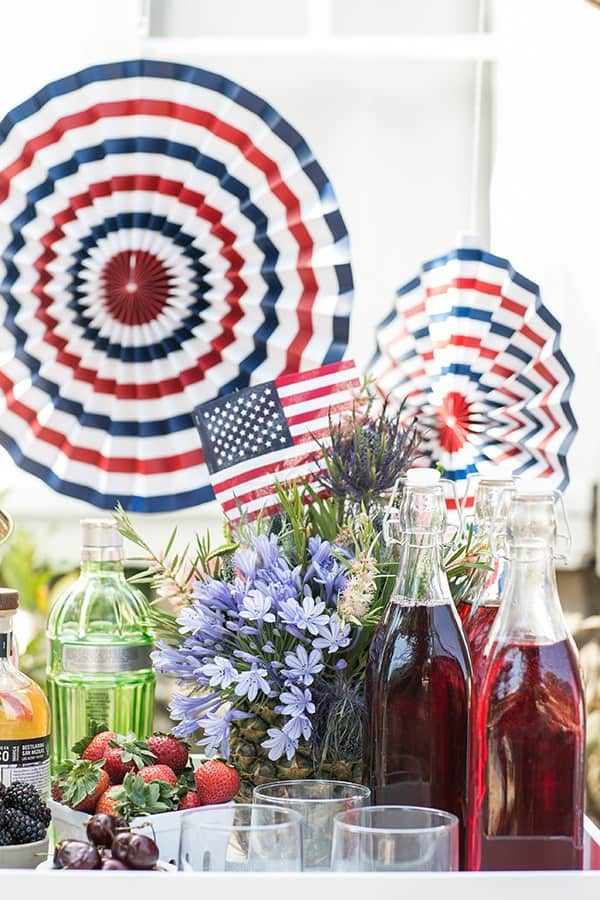 A snow cone bar with syrups, spirits and paper flags.