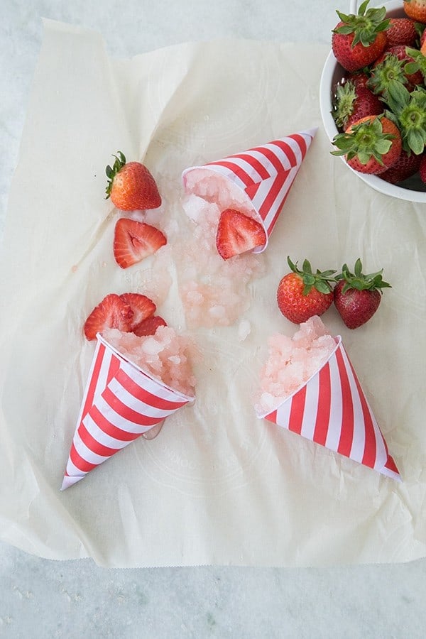 Strawberry snow cones on the table, melted with strawberries.