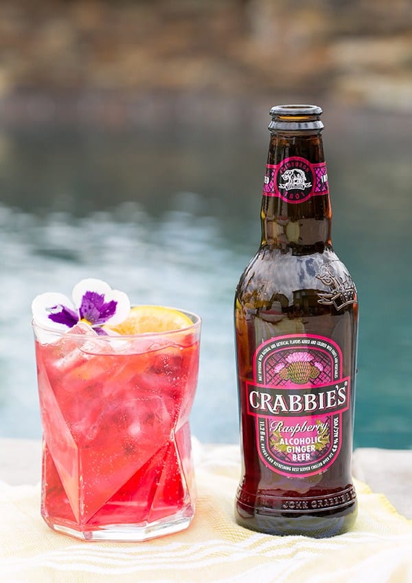 Crabbies ginger beer with a pink cocktail next to it 