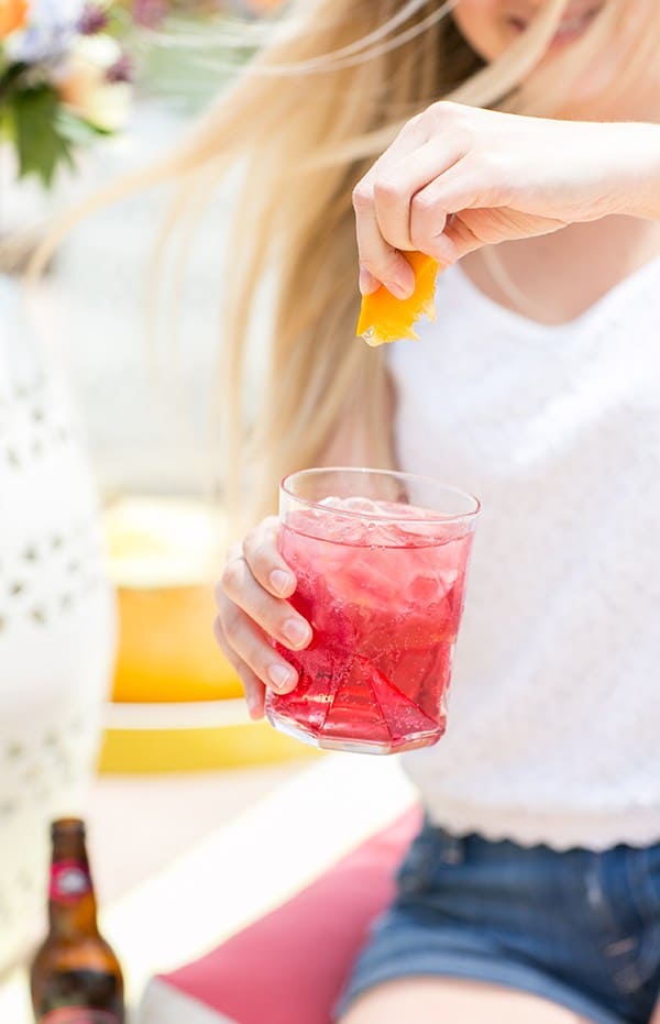 Holding a pink cocktail in hand. 