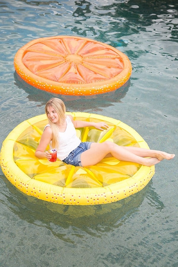 Girl floating on a lemon slice pol float at a pool party 