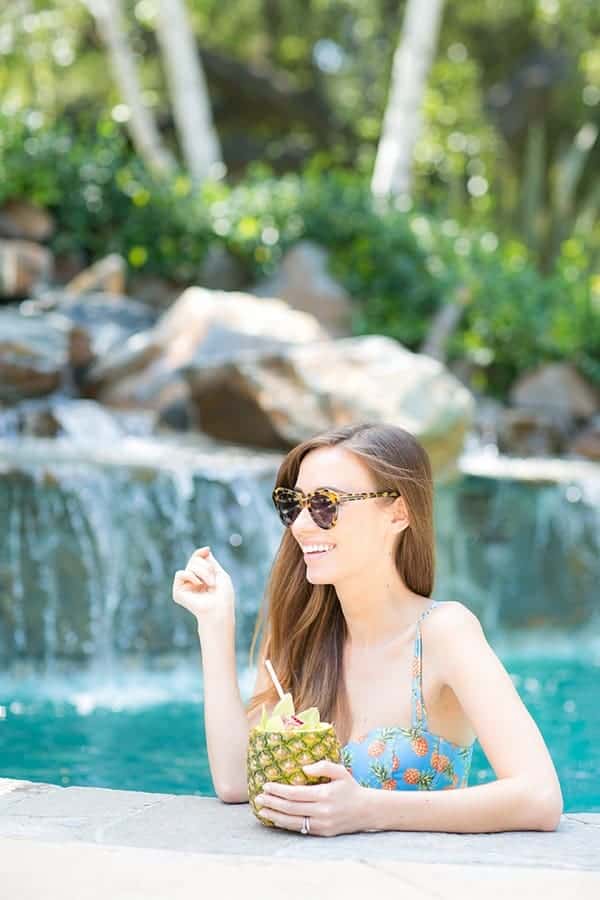 Girl in pineapple bathing suit with a pineapple cocktail at a pool party