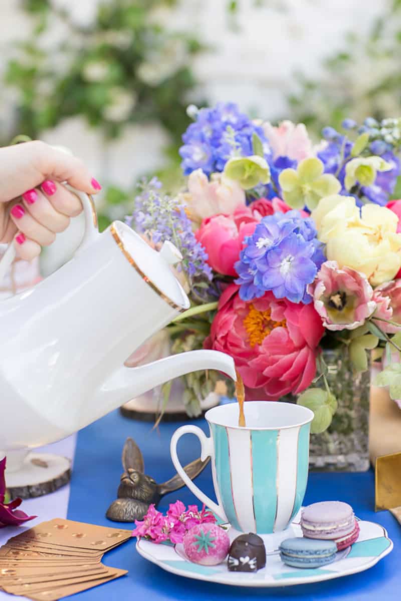 pouring tea into a colorful tea cup for alice in wonderland tea party