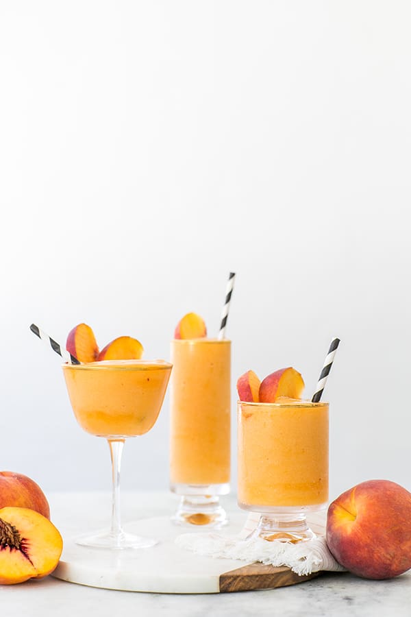 Frozen peach Bellini in different shaped glasses with black and white straws.