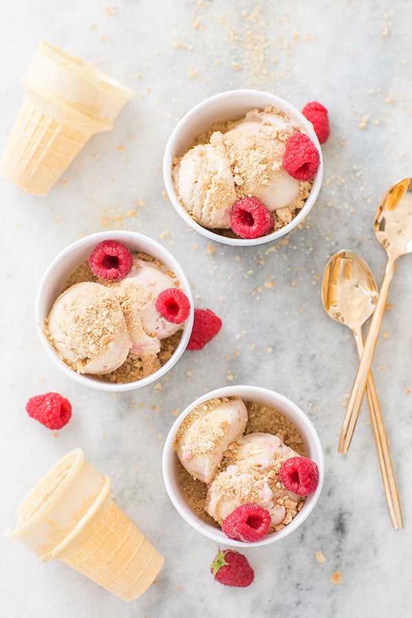 overhead of raspberry swirl cheesecake ice cream with gold spoons and cones