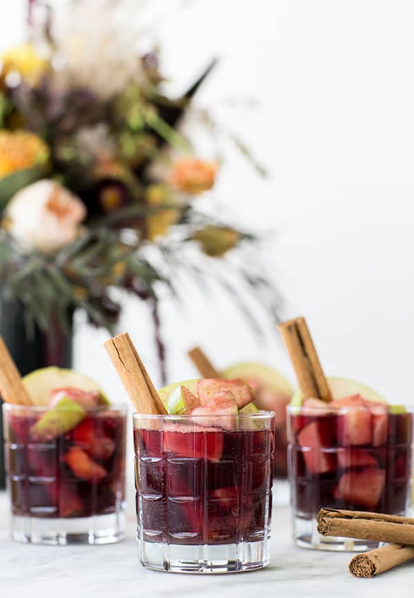 Glasses filled with red sangria and apples.