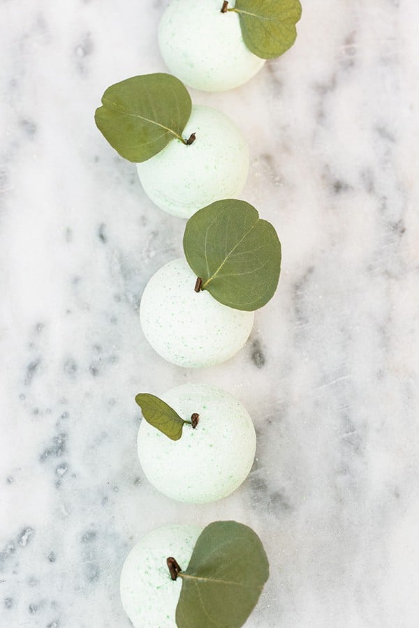 green apple bath bombs in a row on marble