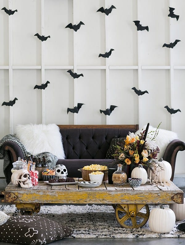 Halloween set-up with black couch, bats on the wall and  rustic table. 