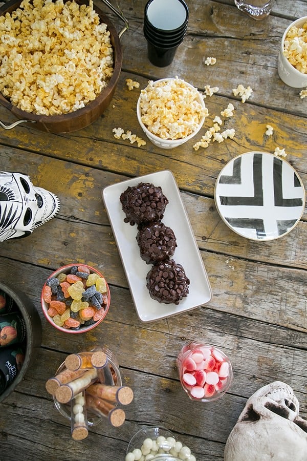 Overhead of Halloween treats and popcorn on wooden table to watch Halloween Movies 