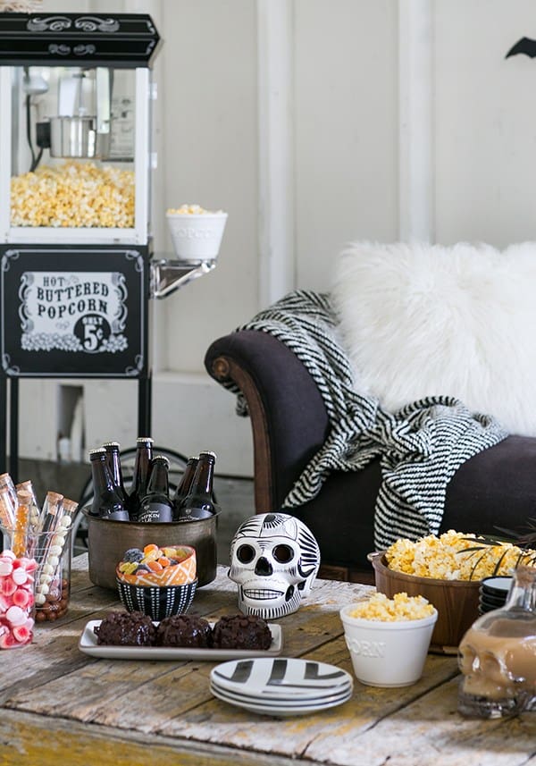 Halloween vintage popcorn machine, with candy and treats on a wooden table set-up to watch Halloween movies.