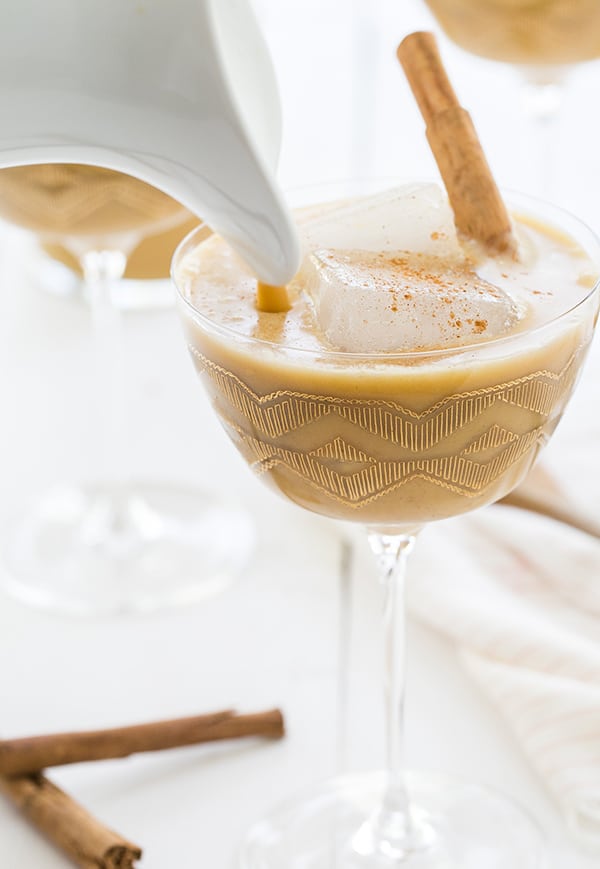 close up of drink being poured into a glass - coconut milk, ice cubes, vanilla extract, spiced rum, cream liqueur