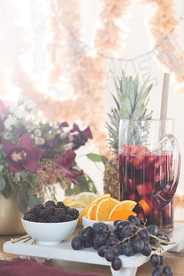 Fruit on a marble tray with a pitcher of sangria.