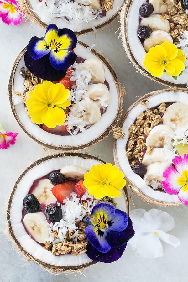 Four coconut acai bowls filled with toppings.