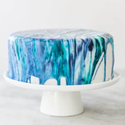 Blue tie-dye frosting dripping from the side of cake