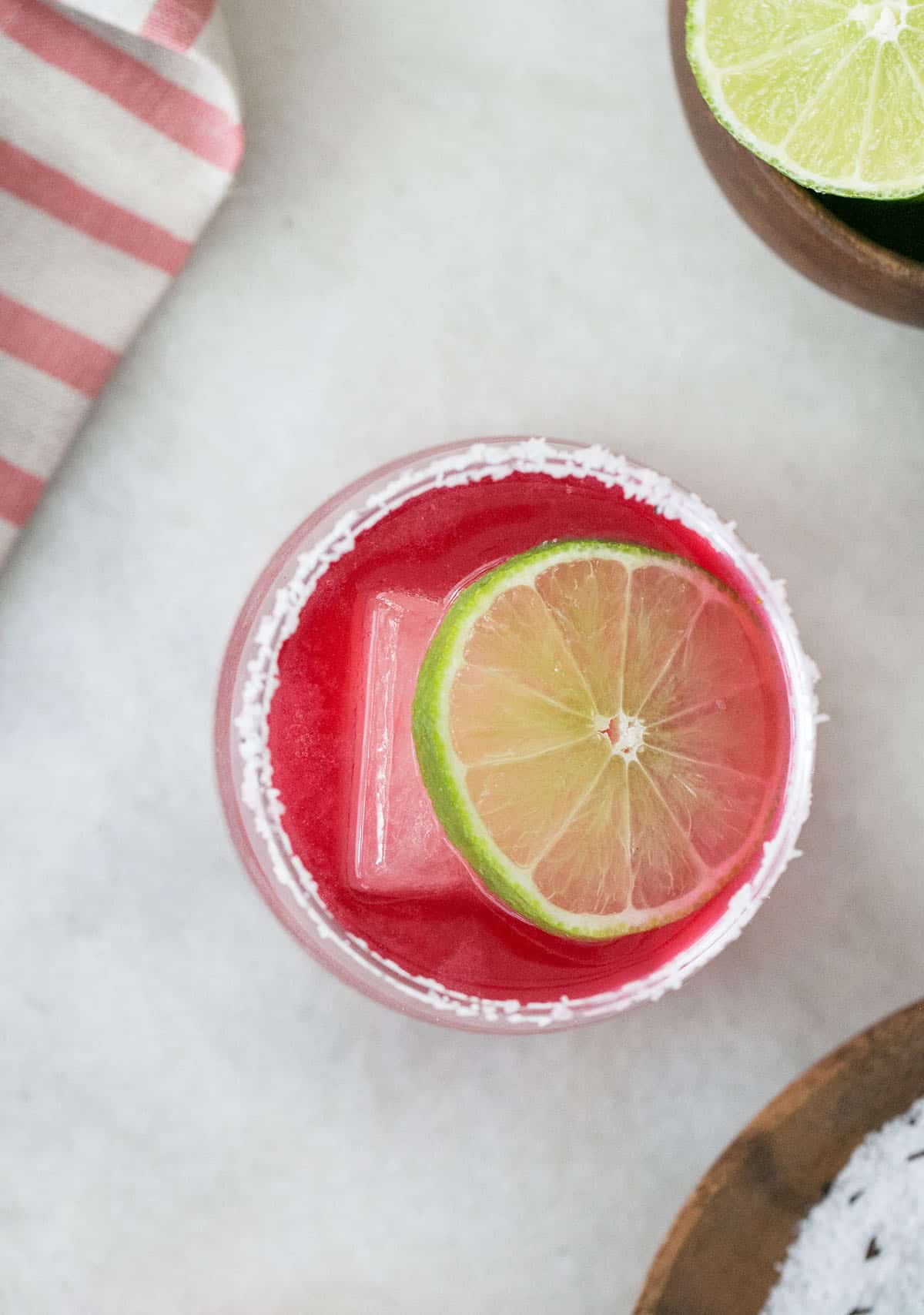 Pink margarita with lime slice and salted rim.