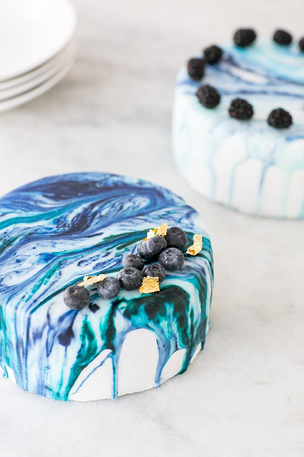 Two marble drip cakes on a work surface