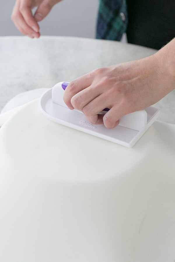 Fondant being smoothed over the cake