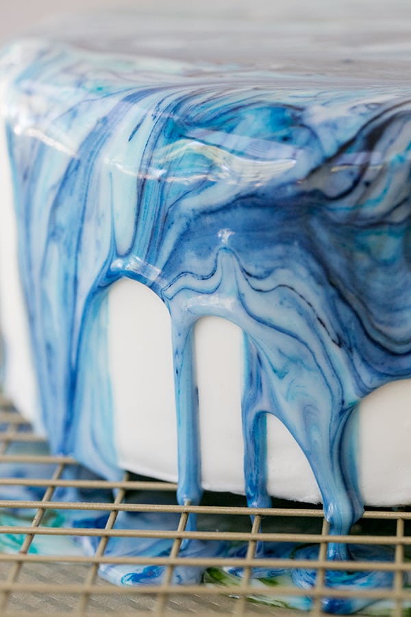 A close up of the side of a marble drip cake.