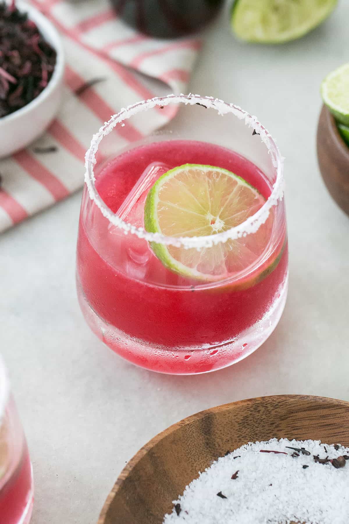 Hibiscus margarita recipe with a salted rim and a lime wheel.