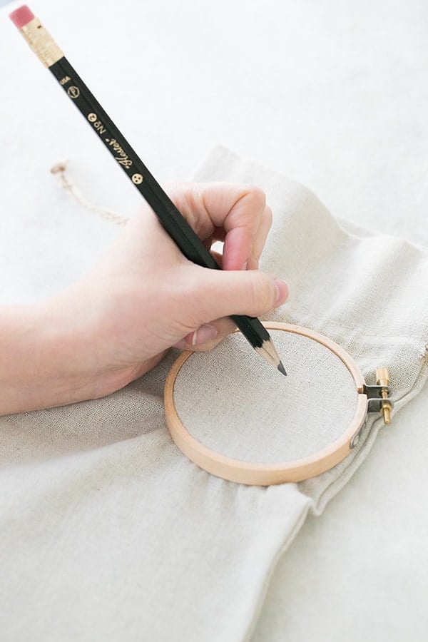 hand writing on a wine bag with an embroidery hoop to make a Valentine's day craft.