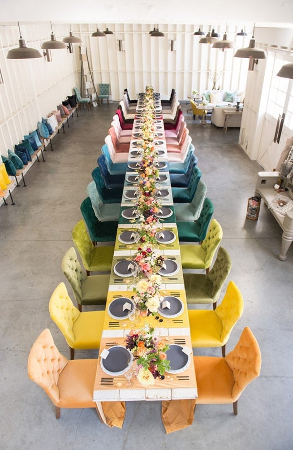 Overhead of colorful chairs going down the center of a table.