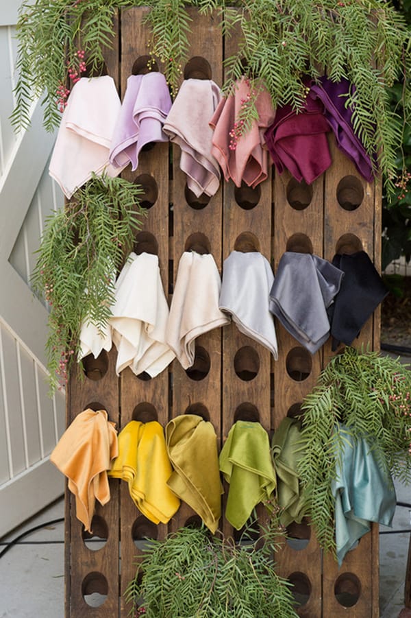 Colorful table linens in a wooden wine rack.