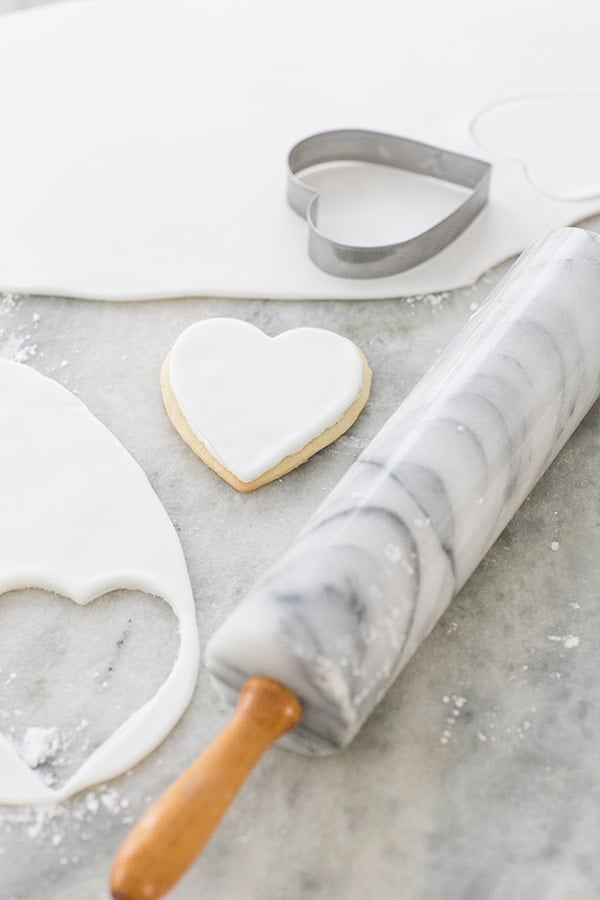 cookie dough being cut into heart shapes with a cookie cutter