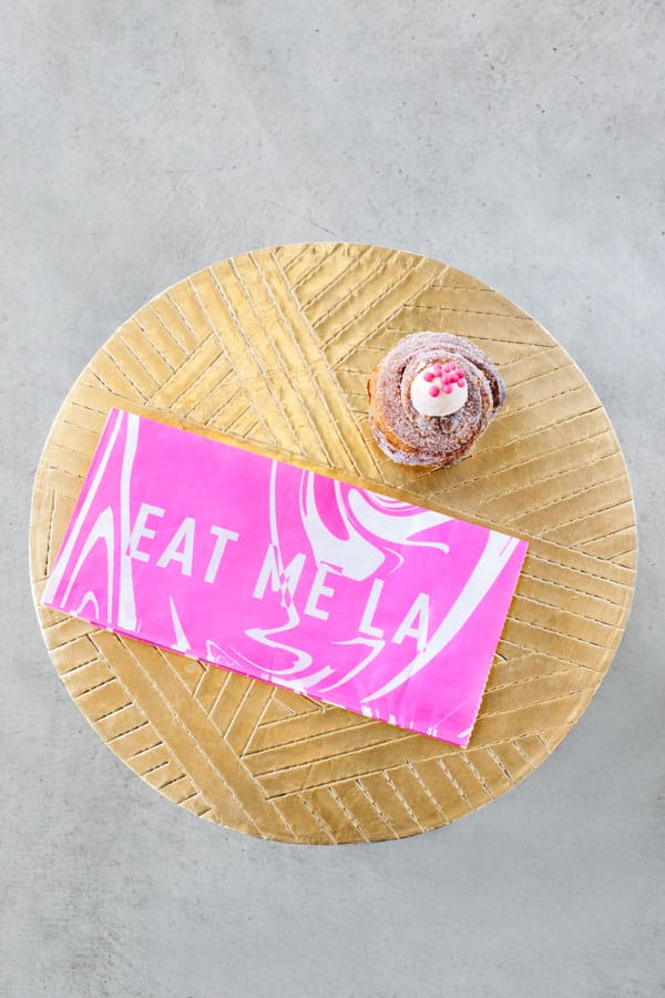 Cruffin and pink bag on a gold table. 