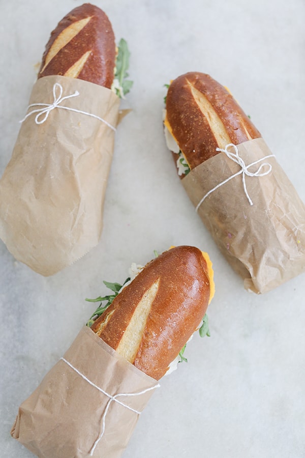 Sandwiches on pretzel bread with brown paper and twine.