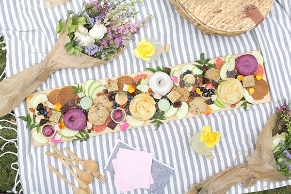 Board with treats on a picnic blanket