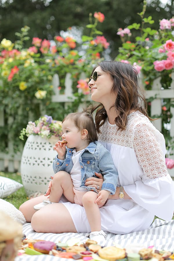 Woman holding her toddler at a Mother's Day picnic. 