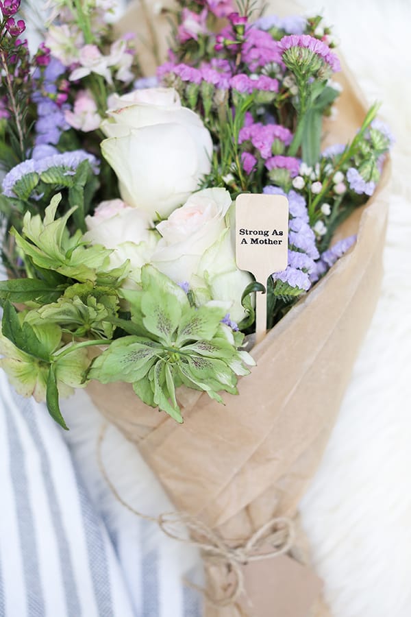 Bouquet of flowers with a wooden sign that says strong as a mother.