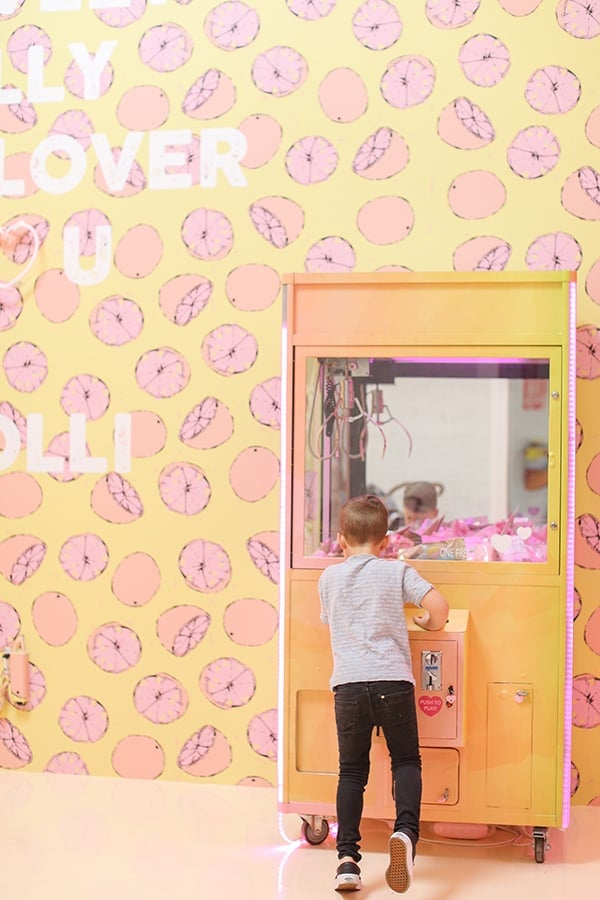 Little boy playing a vending machine with lemon wallpaper.