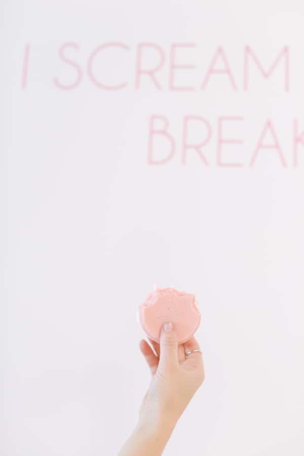 Hand holding up a pink ice cream sandwich.