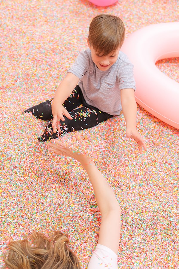 Little boy and mom tossing sprinkles at the museum of ice cream.
