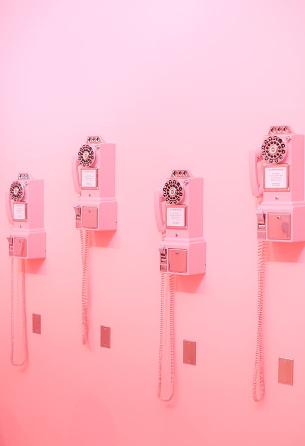 Pink telephones on a pink wall. 