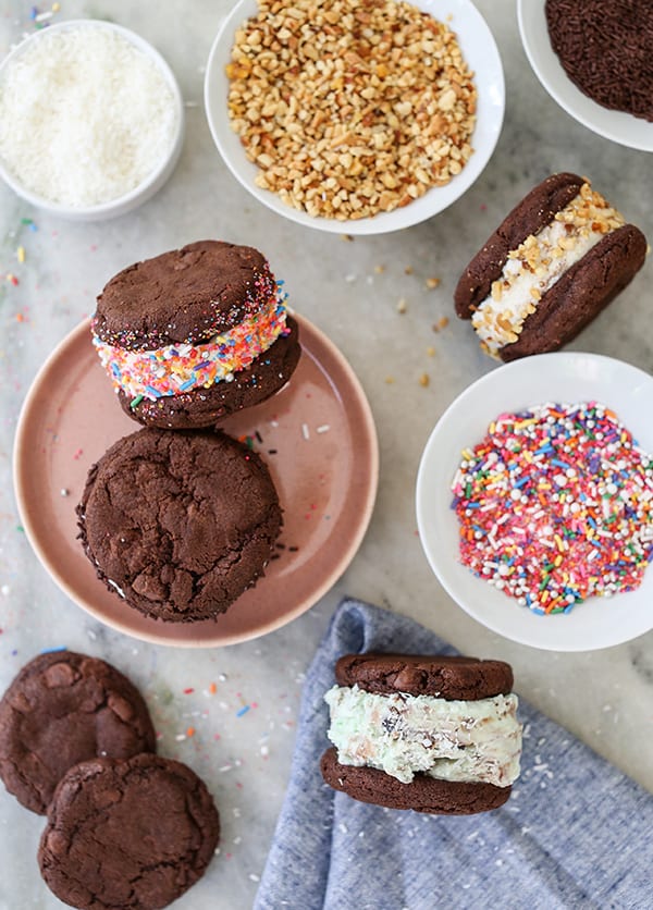 Cookie ice cream sandwiches on a table with sprinkles.