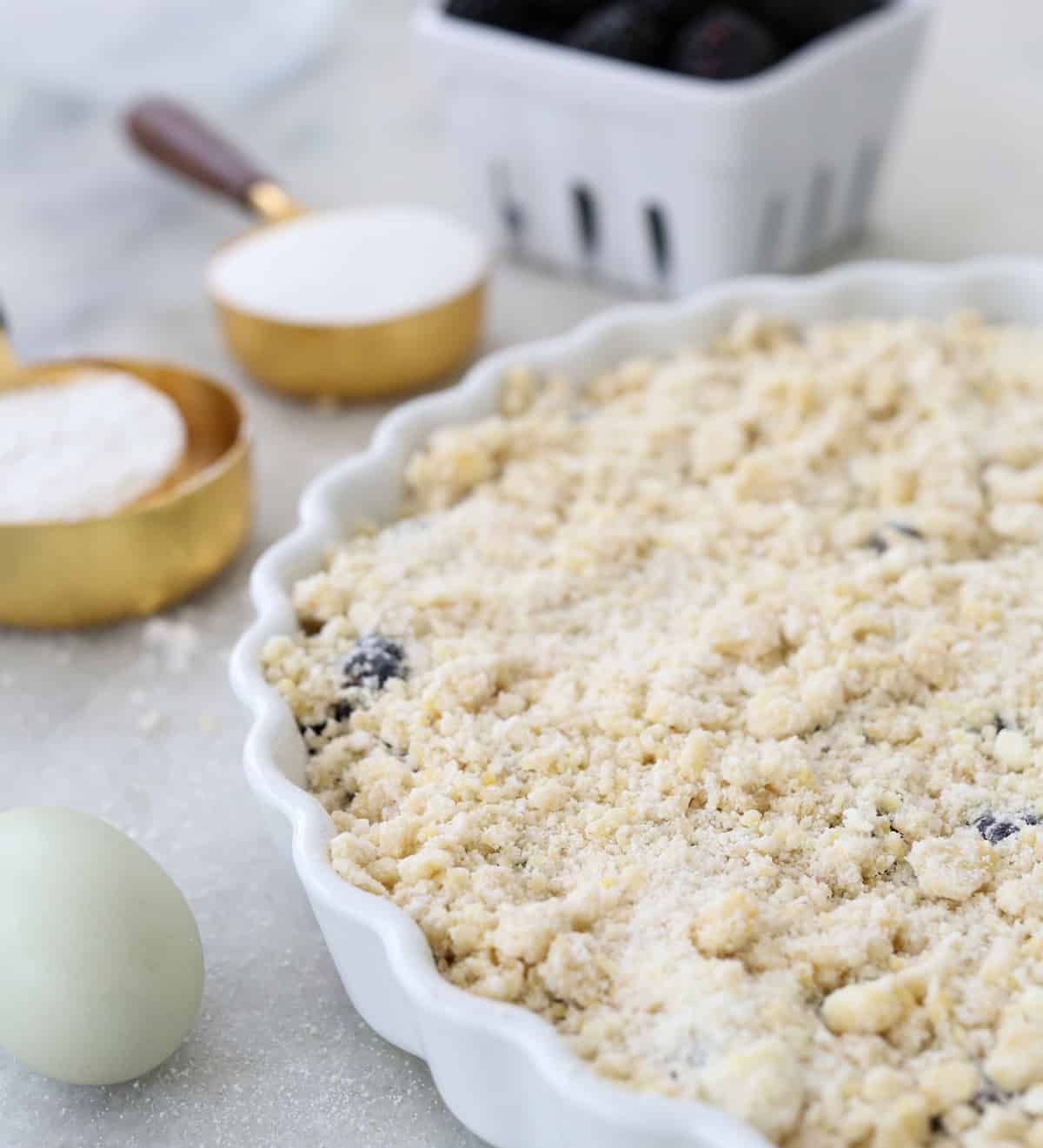 Brombeer-Cobbler vor dem Backen in einer Kuchenform zerbröseln.