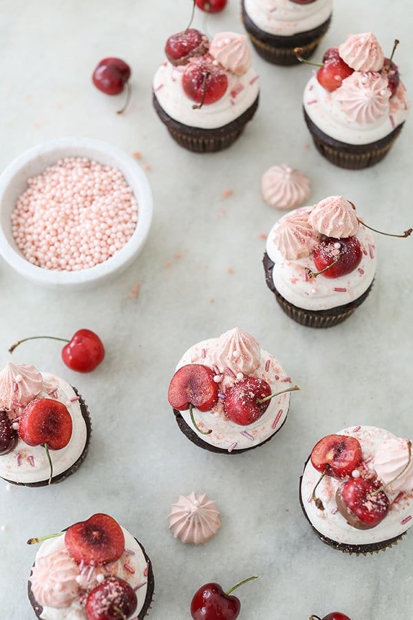 Chocolate cherry cupcakes on a marble table with sprinkles. 
