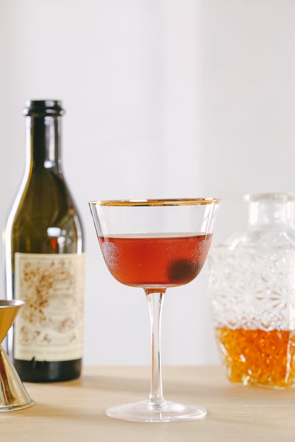 A classic Manhattan cocktail in a coupe glass with a cherry on the bottom.