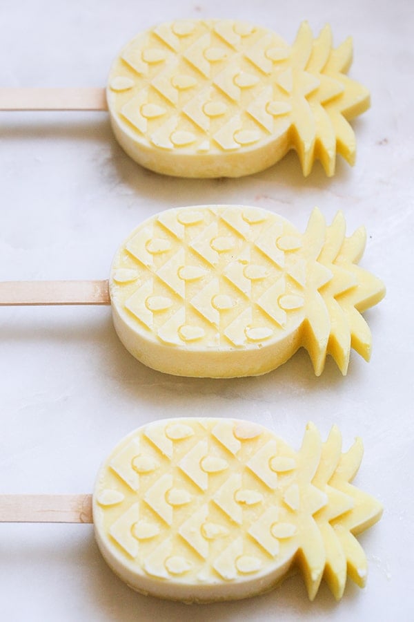 top down shot of three pineapple popsicles shaped as pineapples.